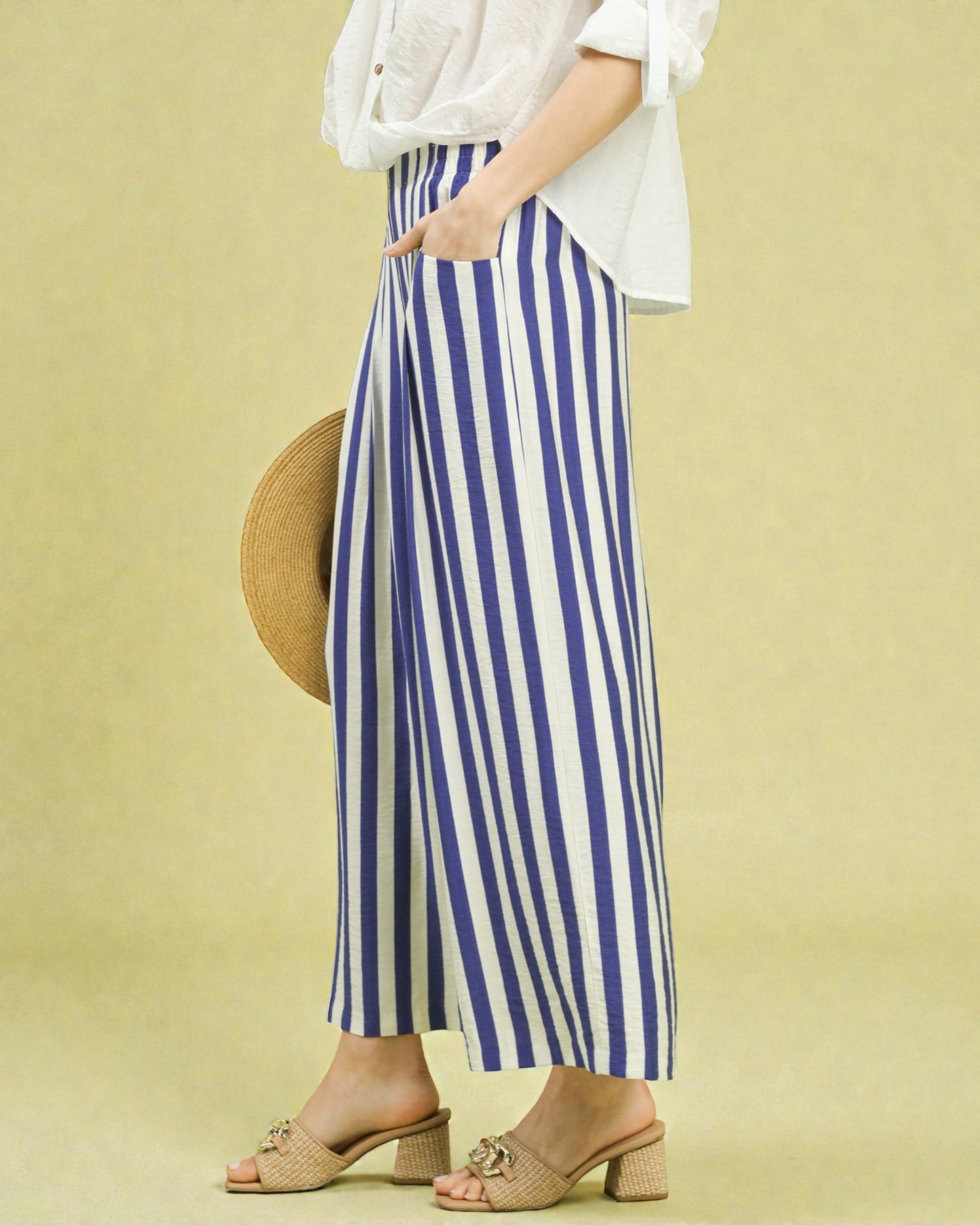 Person wearing a white top and blue and white striped pants on a yellow background
