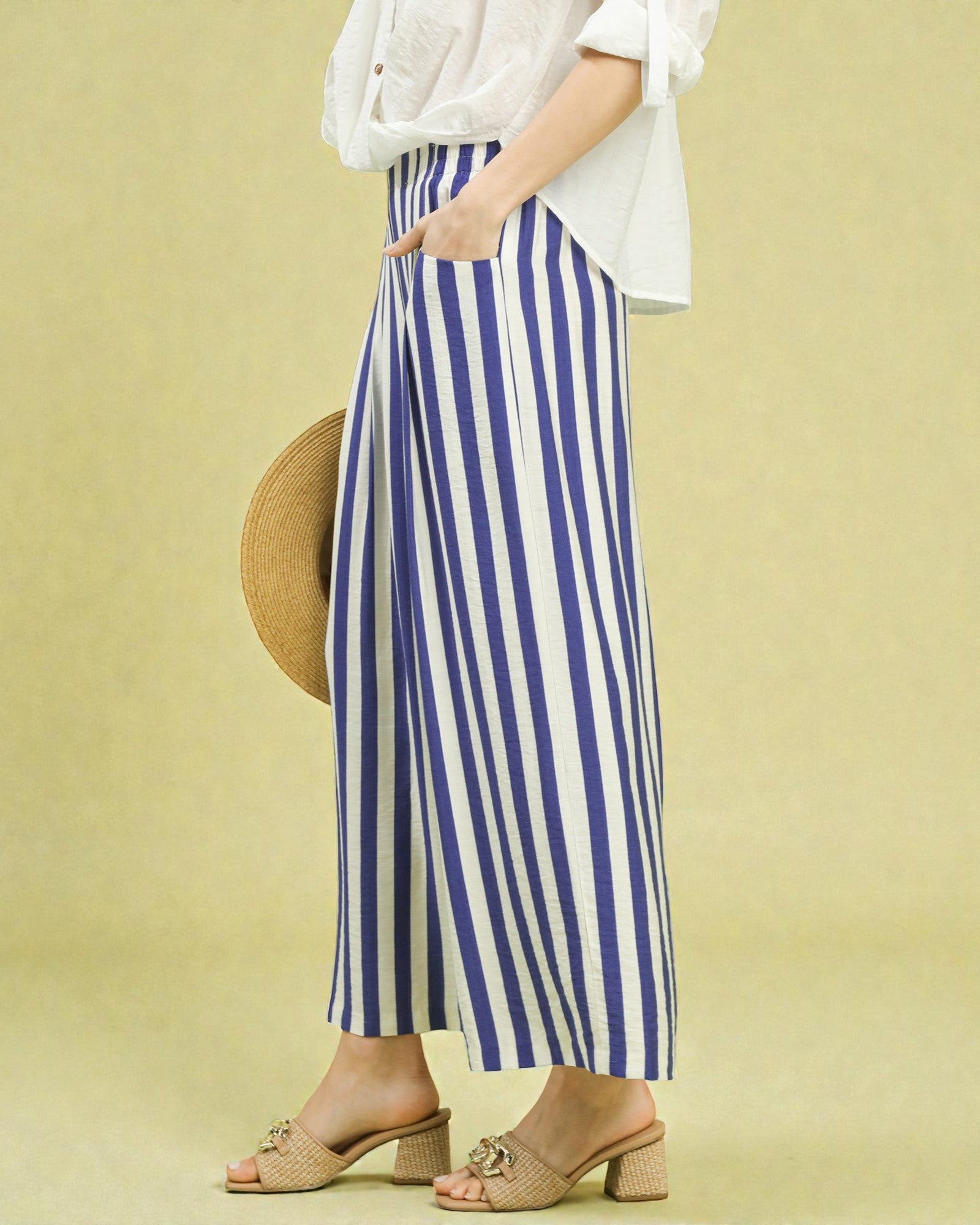 Person wearing a white top and blue and white striped pants on a yellow background