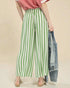 Person wearing green and white striped pants with a pink top and beige background