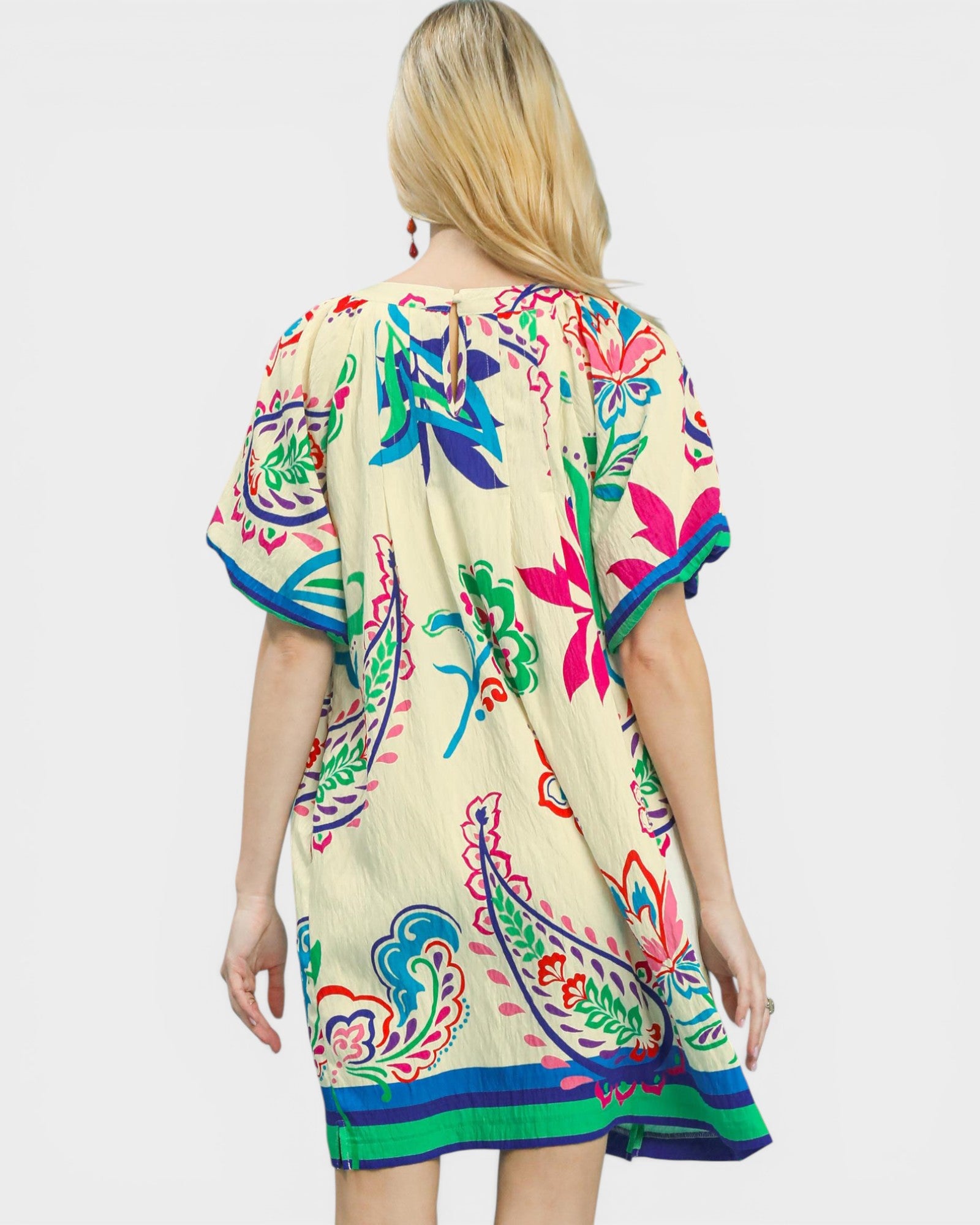 Woman wearing a colorful dress with floral patterns on a white background