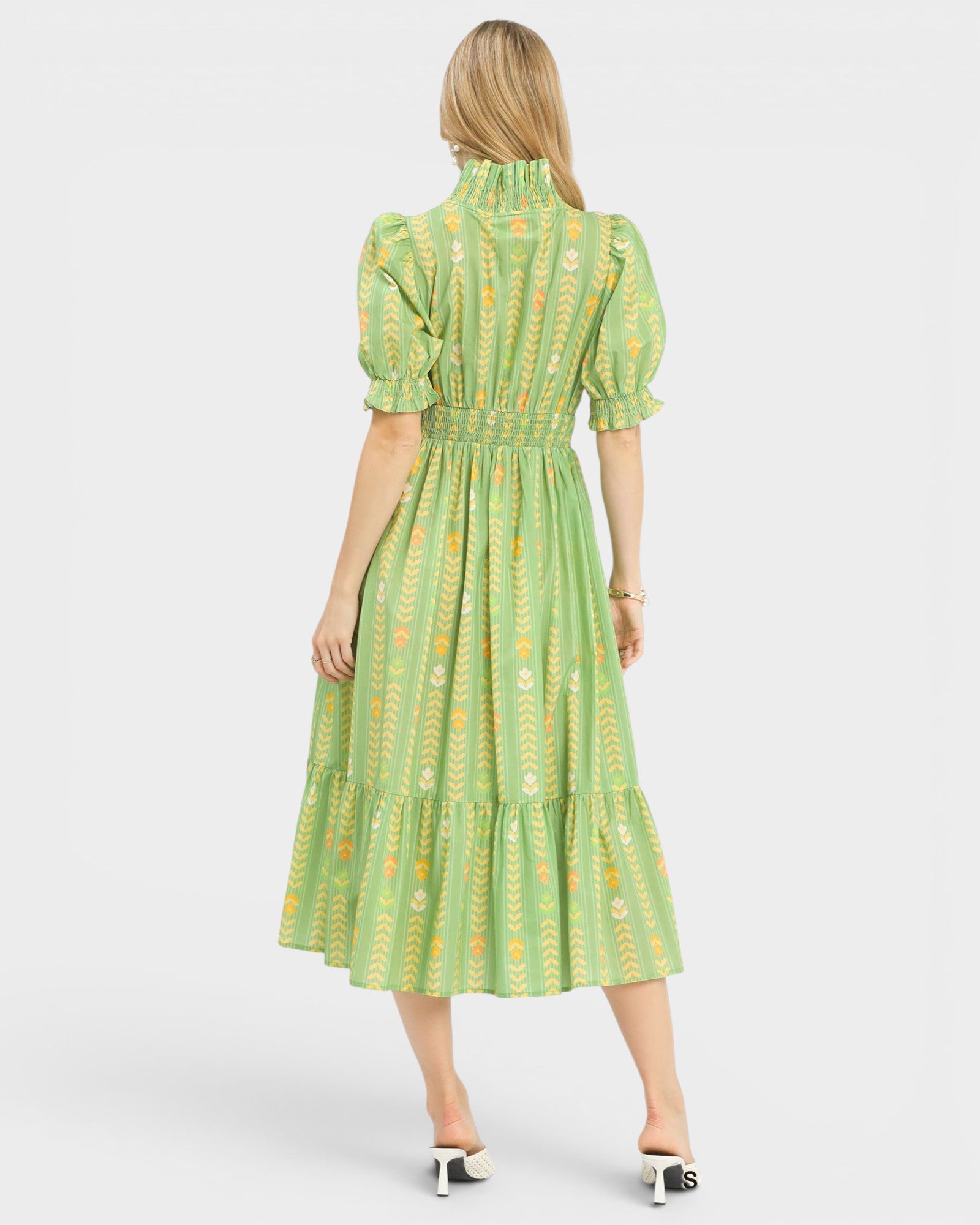 Woman wearing a green dress with a floral pattern on a white background
