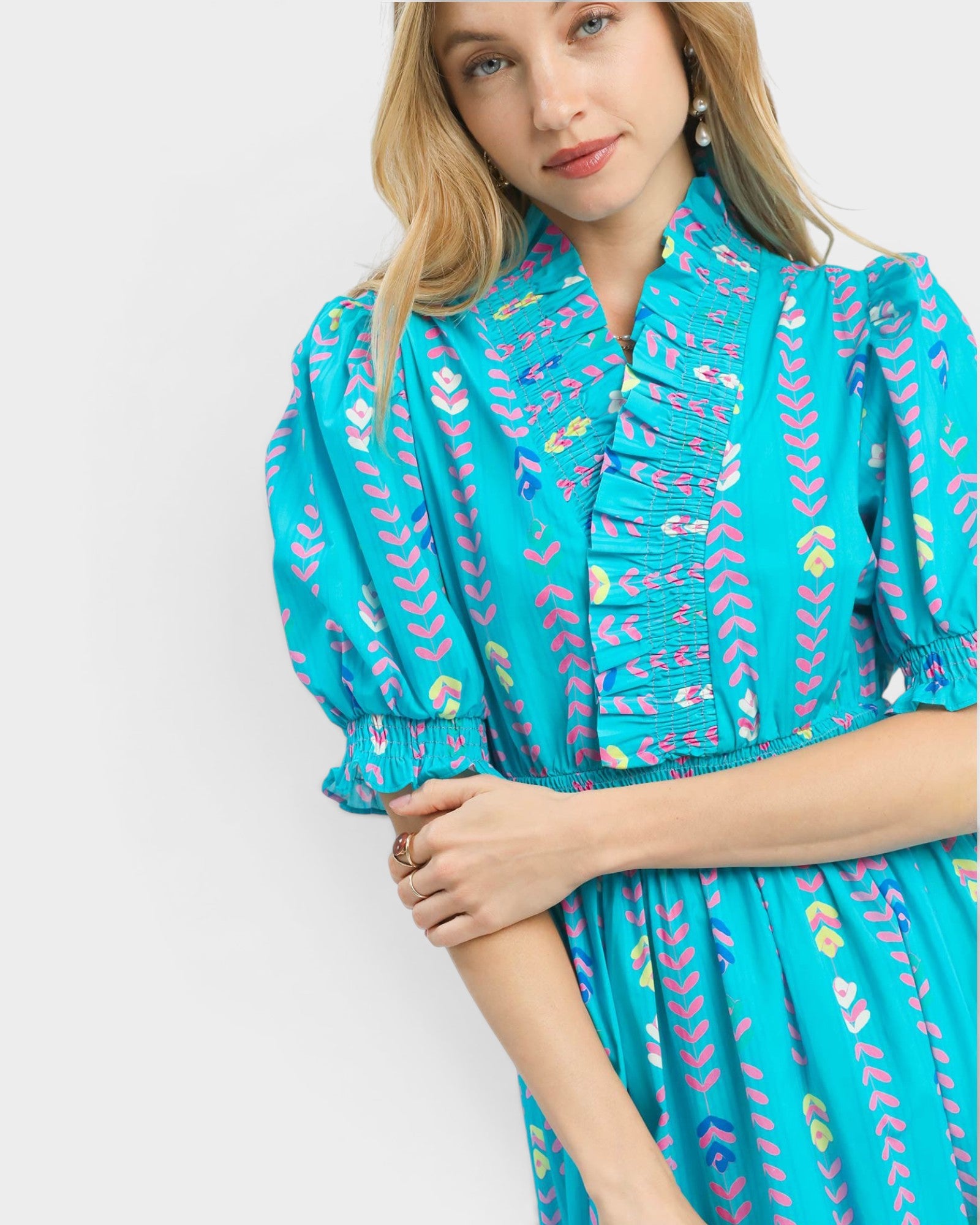 Woman wearing a turquoise dress with colorful patterns on a white background