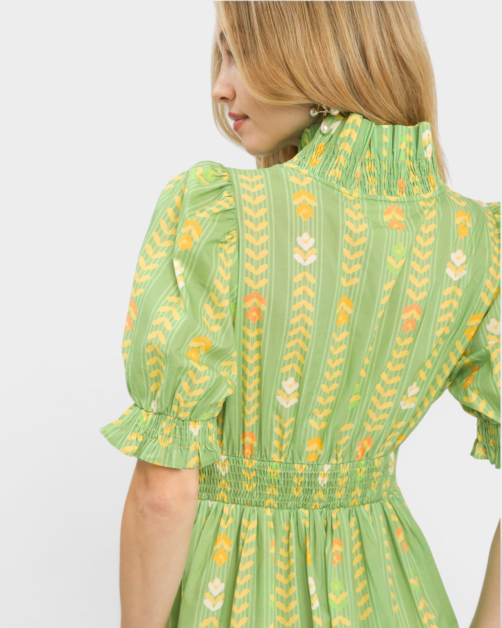 Green dress with floral pattern worn by a person on a white background