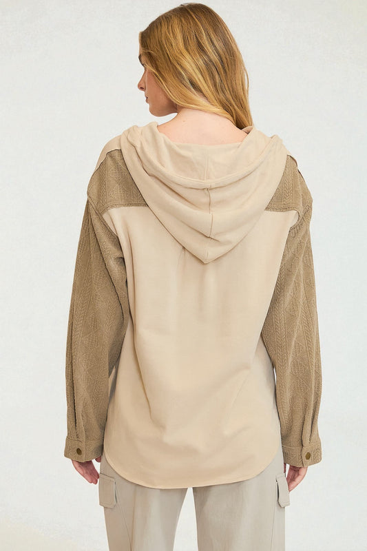 Woman wearing a beige and brown hooded jacket on a white background