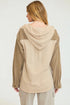 Woman wearing a beige and brown hooded jacket on a white background