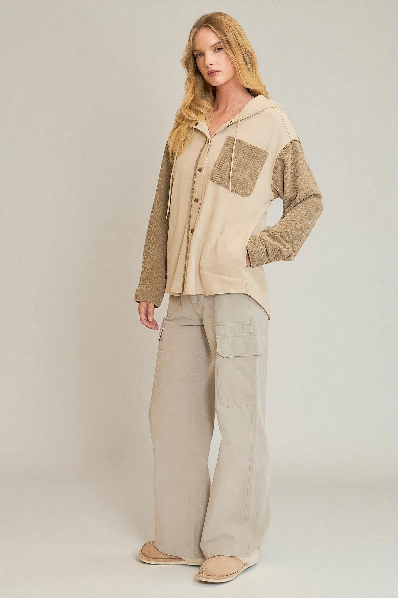 Woman wearing a beige and brown outfit with wide-leg pants on a plain background