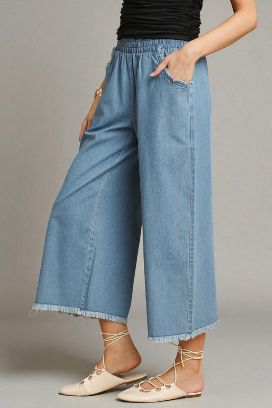 Person wearing blue denim wide-leg pants on a gray background