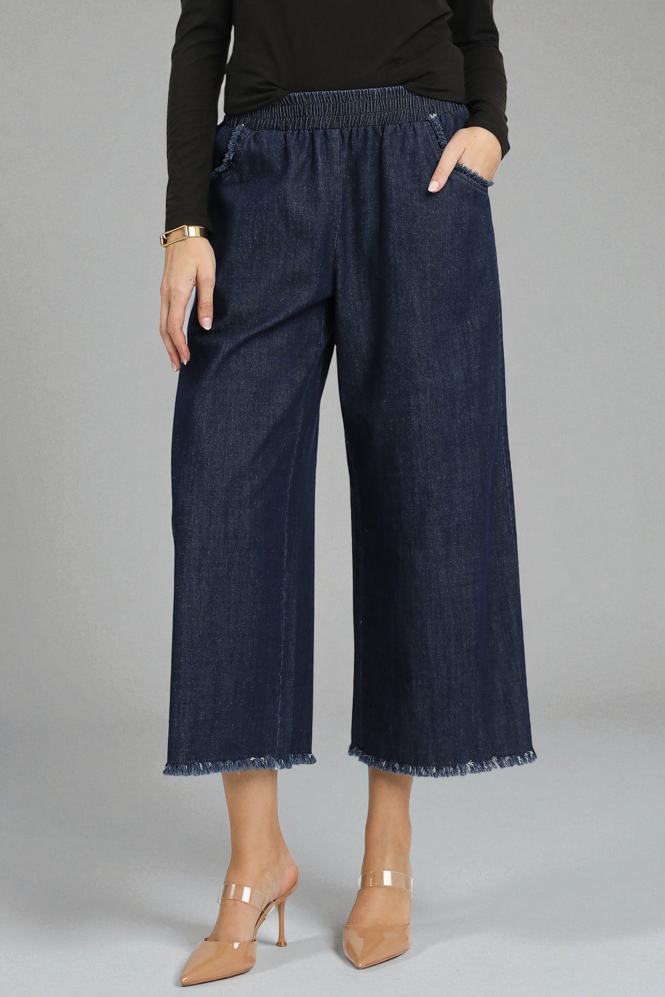 Dark blue denim pants worn by a person on a gray background