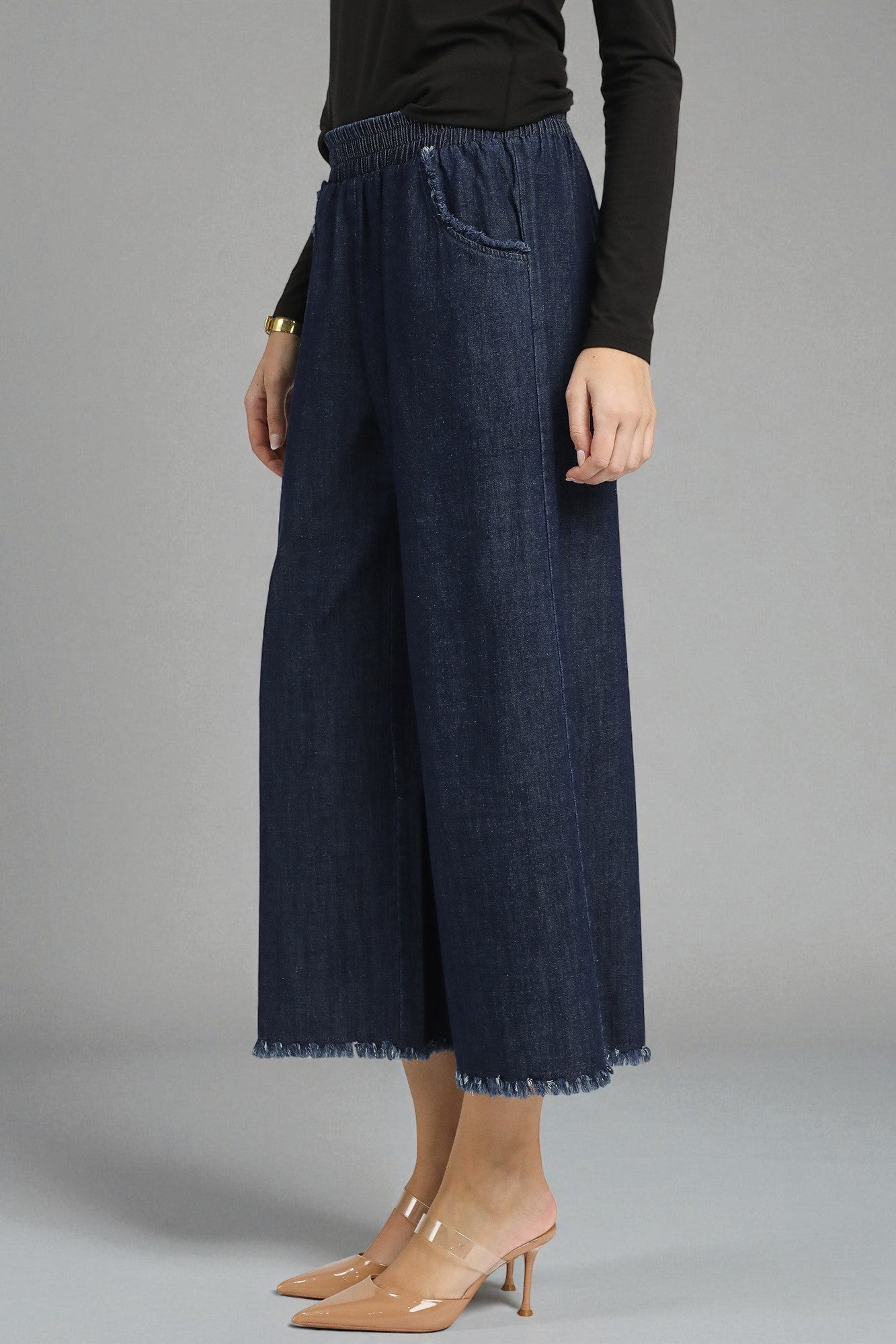 Person wearing dark blue denim pants on a gray background