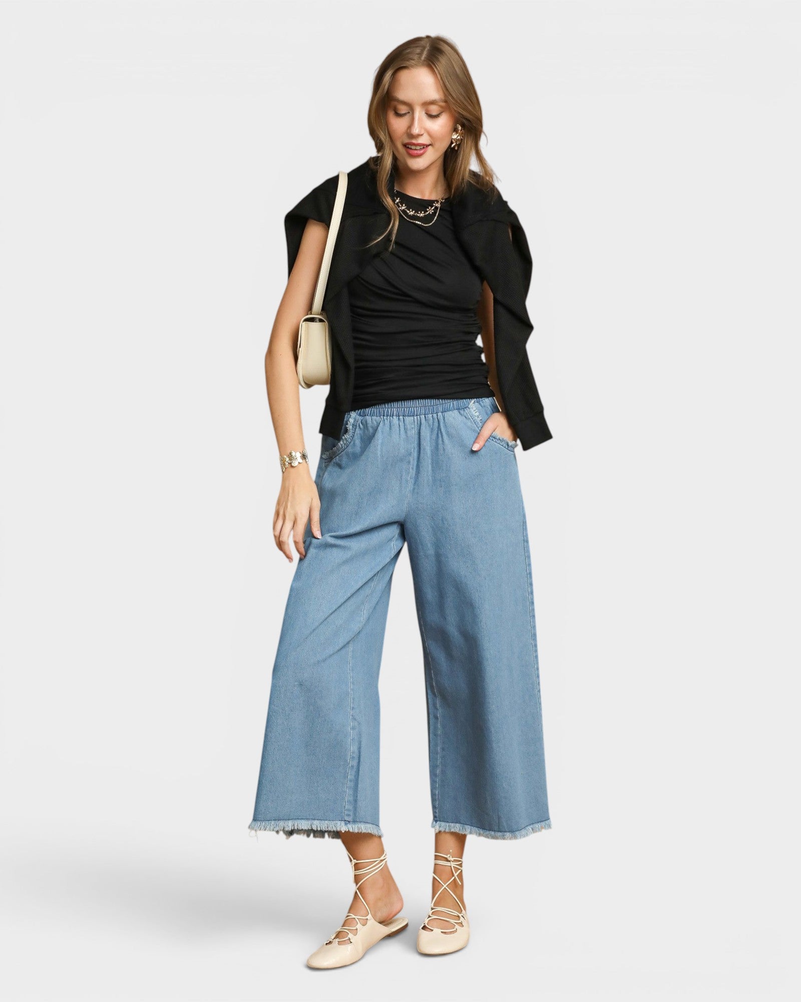 Woman wearing a black jacket, black top, and blue jeans on a white background