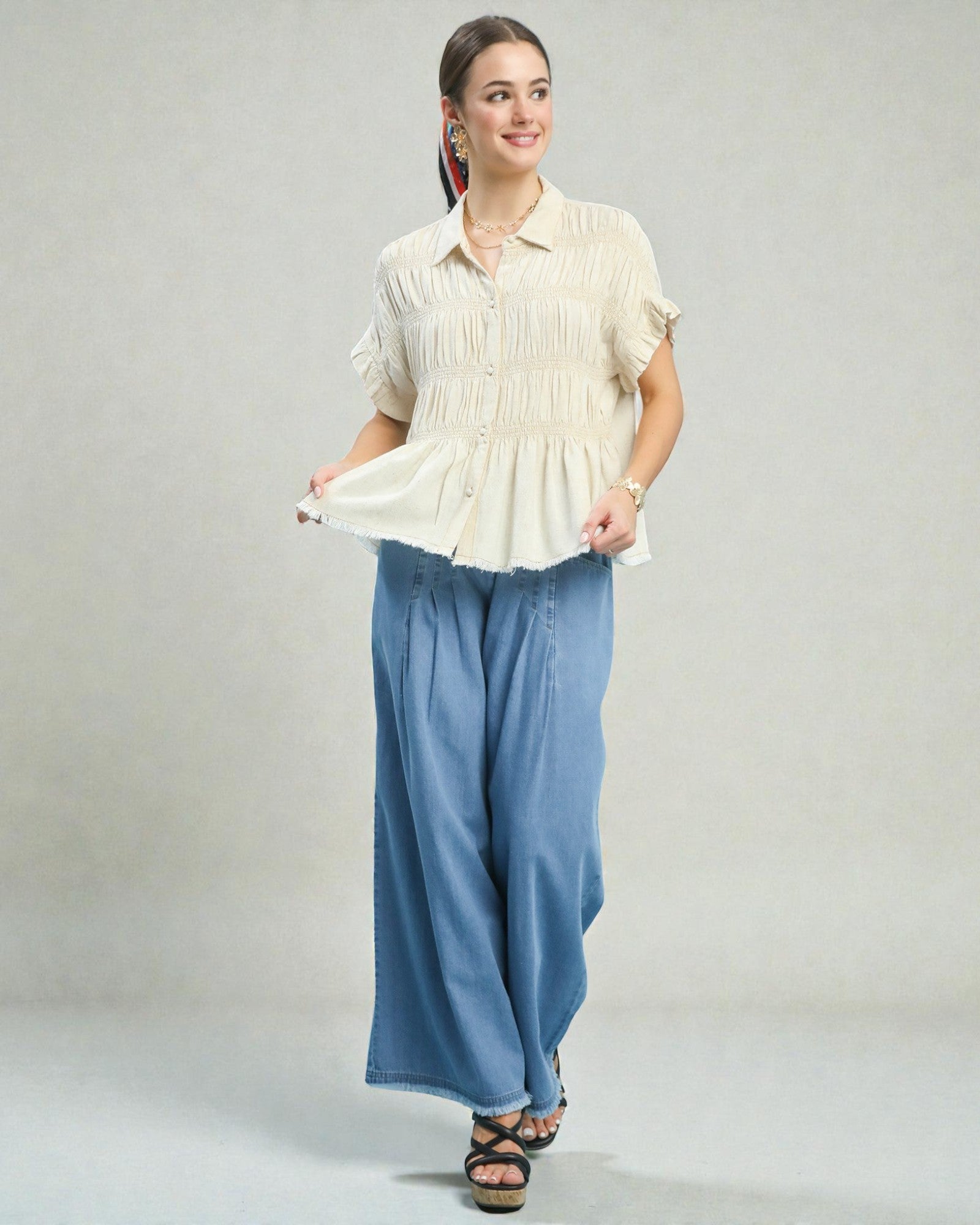 Woman wearing a white blouse and blue pants on a gray background