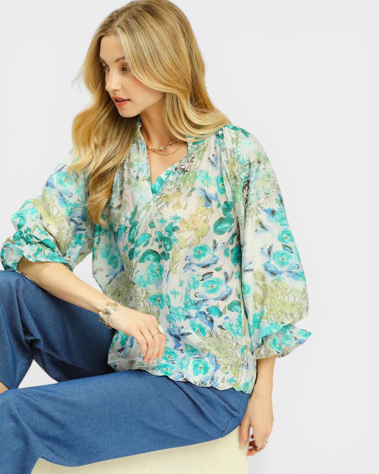 Woman wearing a floral blouse and blue pants on a white background