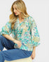 Woman wearing a floral blouse and blue pants on a white background