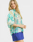 Woman wearing a floral blouse and blue shorts on a white background