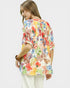 Woman wearing a colorful floral blouse on a white background