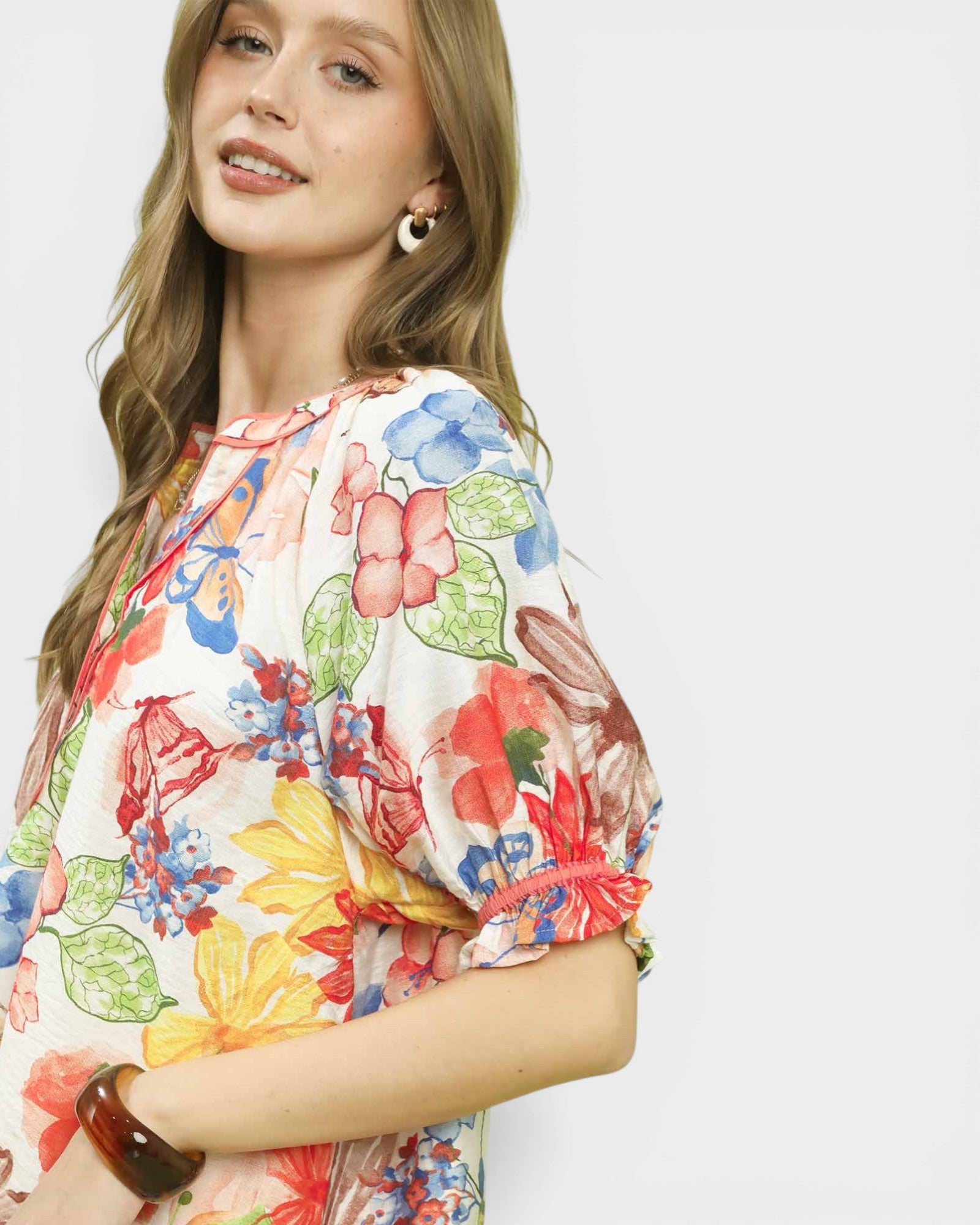 Woman wearing a colorful floral dress against a white background