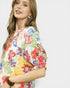 Woman wearing a colorful floral dress against a white background