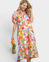 Woman wearing a colorful floral dress against a white background