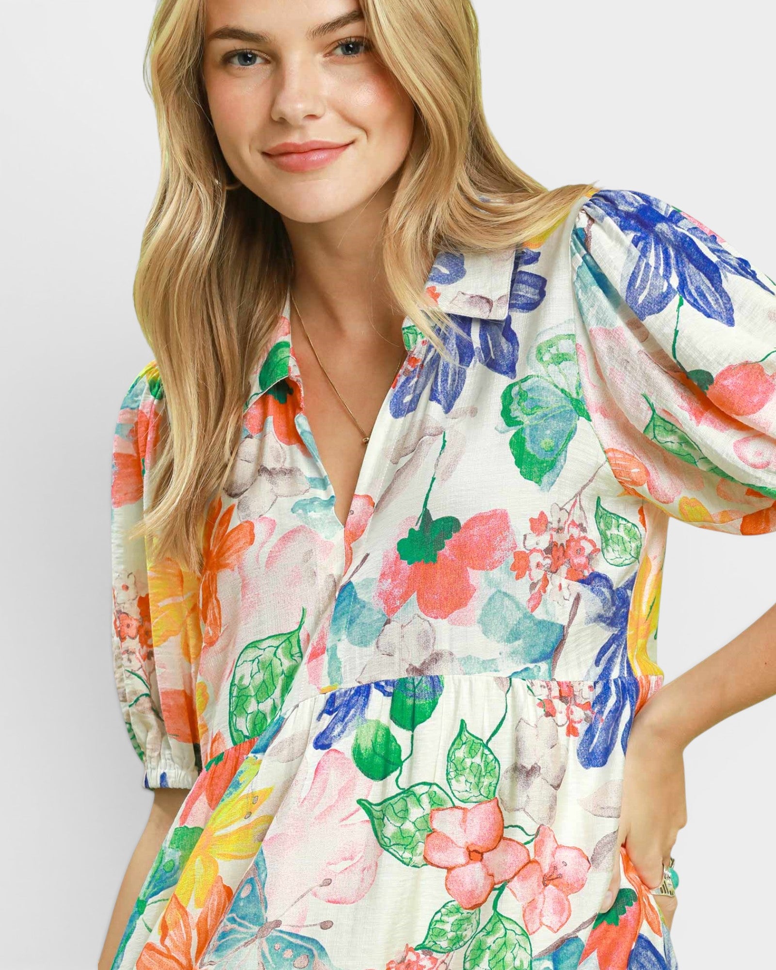 Woman wearing a colorful floral dress against a plain background