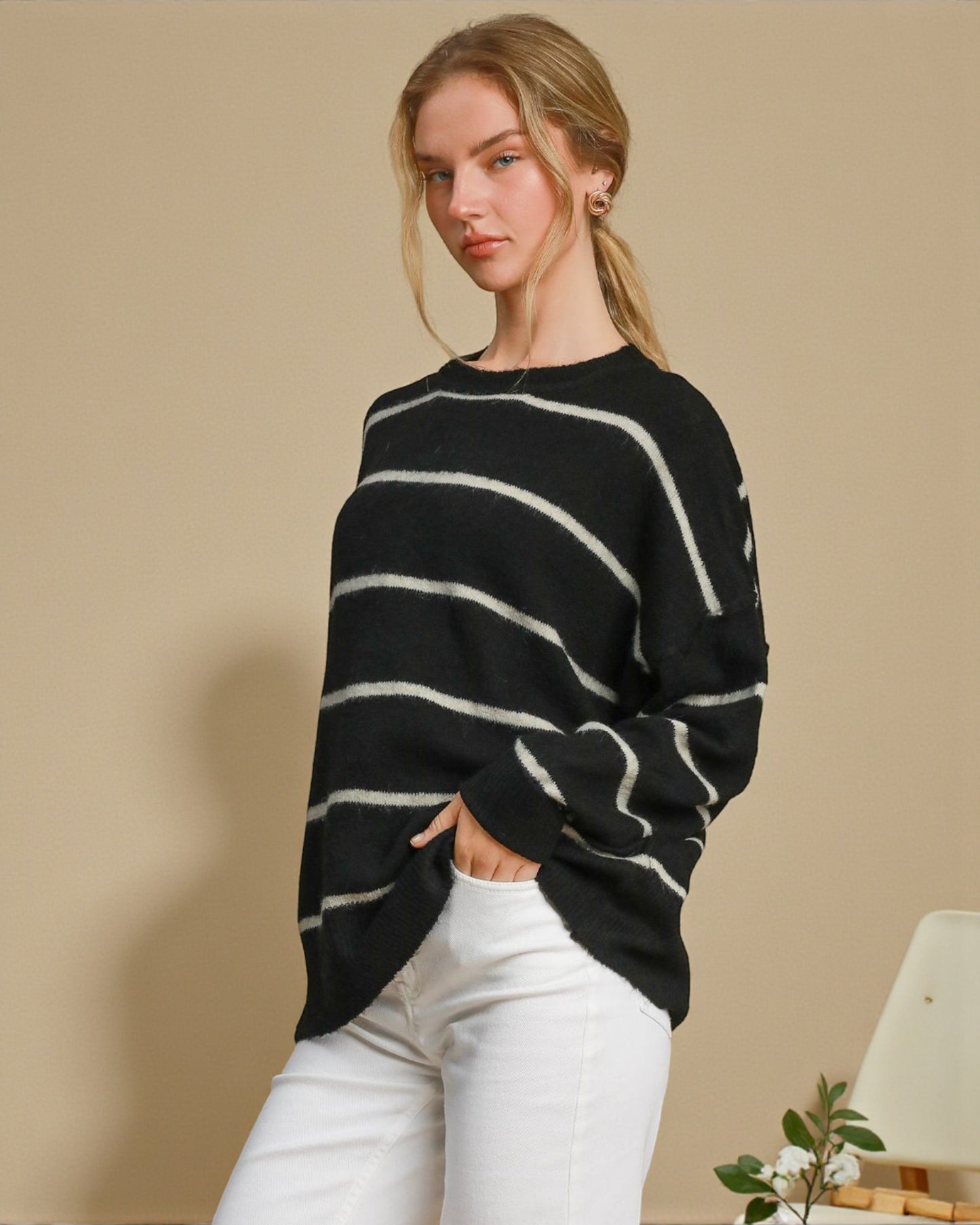 Woman wearing a black and white striped sweater against a beige background