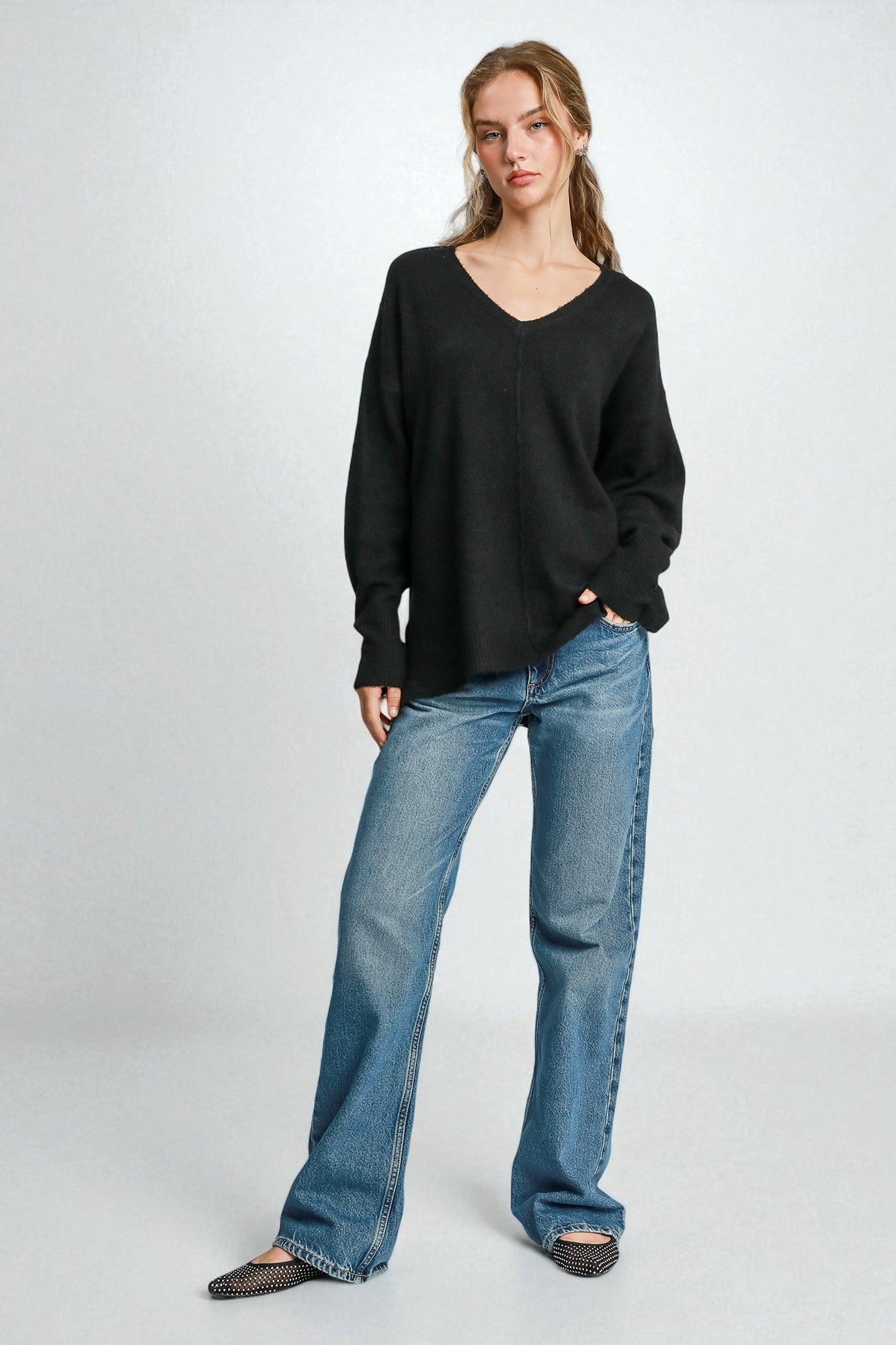 Woman wearing a black sweater and blue jeans on a white background