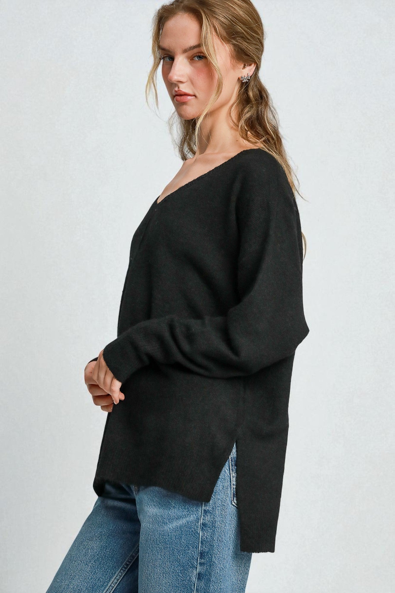 Woman wearing a black sweater and blue jeans on a white background