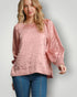 Woman wearing a pink textured top and blue jeans on a plain background