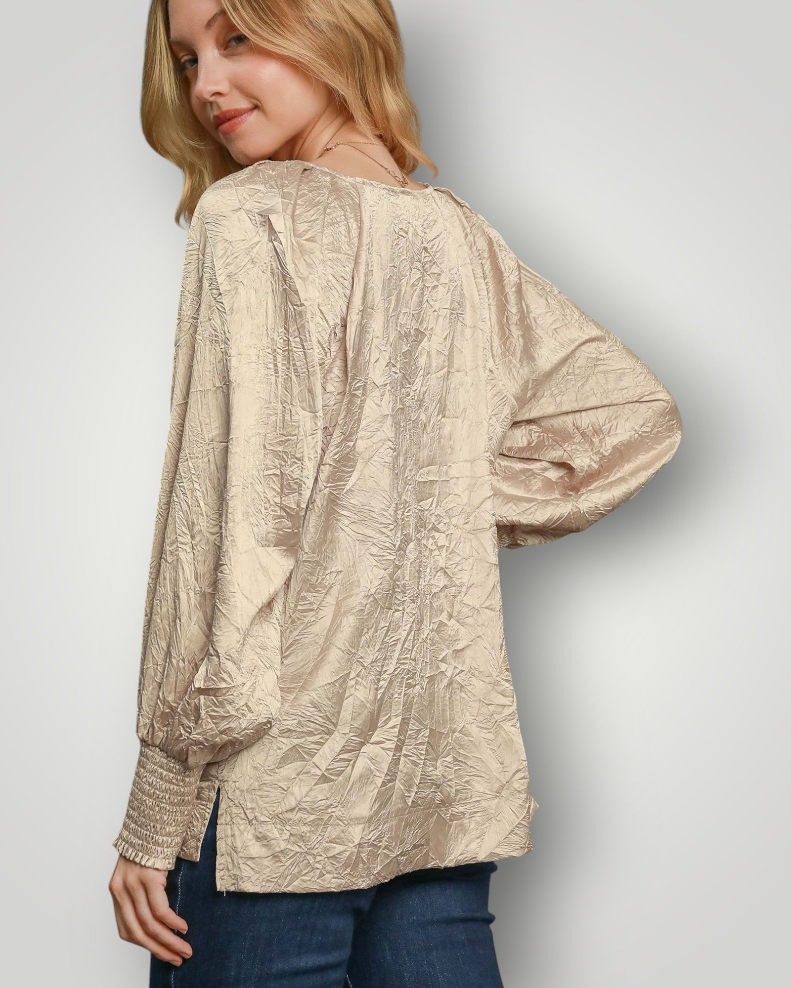 Woman wearing a textured beige blouse against a plain background