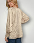 Woman wearing a textured beige blouse against a plain background