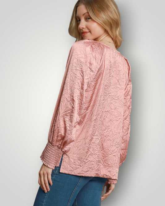 Woman wearing a pink textured blouse and blue jeans on a light gray background