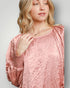 Woman wearing a pink textured dress against a plain background