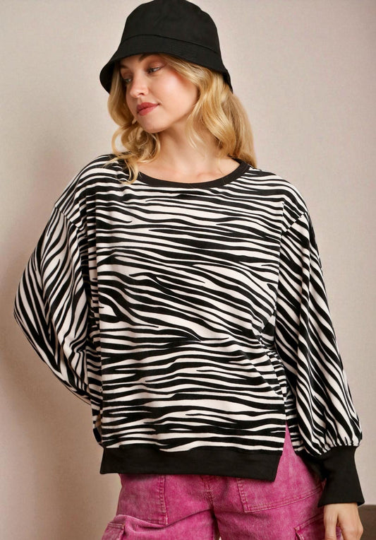 Woman wearing a zebra print sweater and pink pants against a plain background