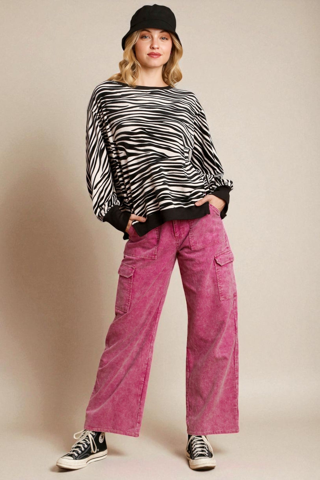 Person wearing a zebra print sweater and pink pants against a beige background