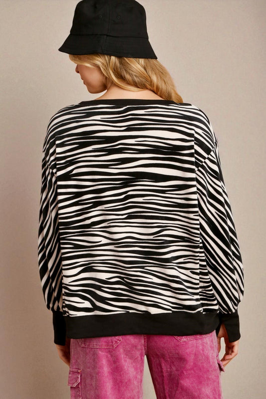 Person wearing a zebra print sweater and pink pants against a neutral background