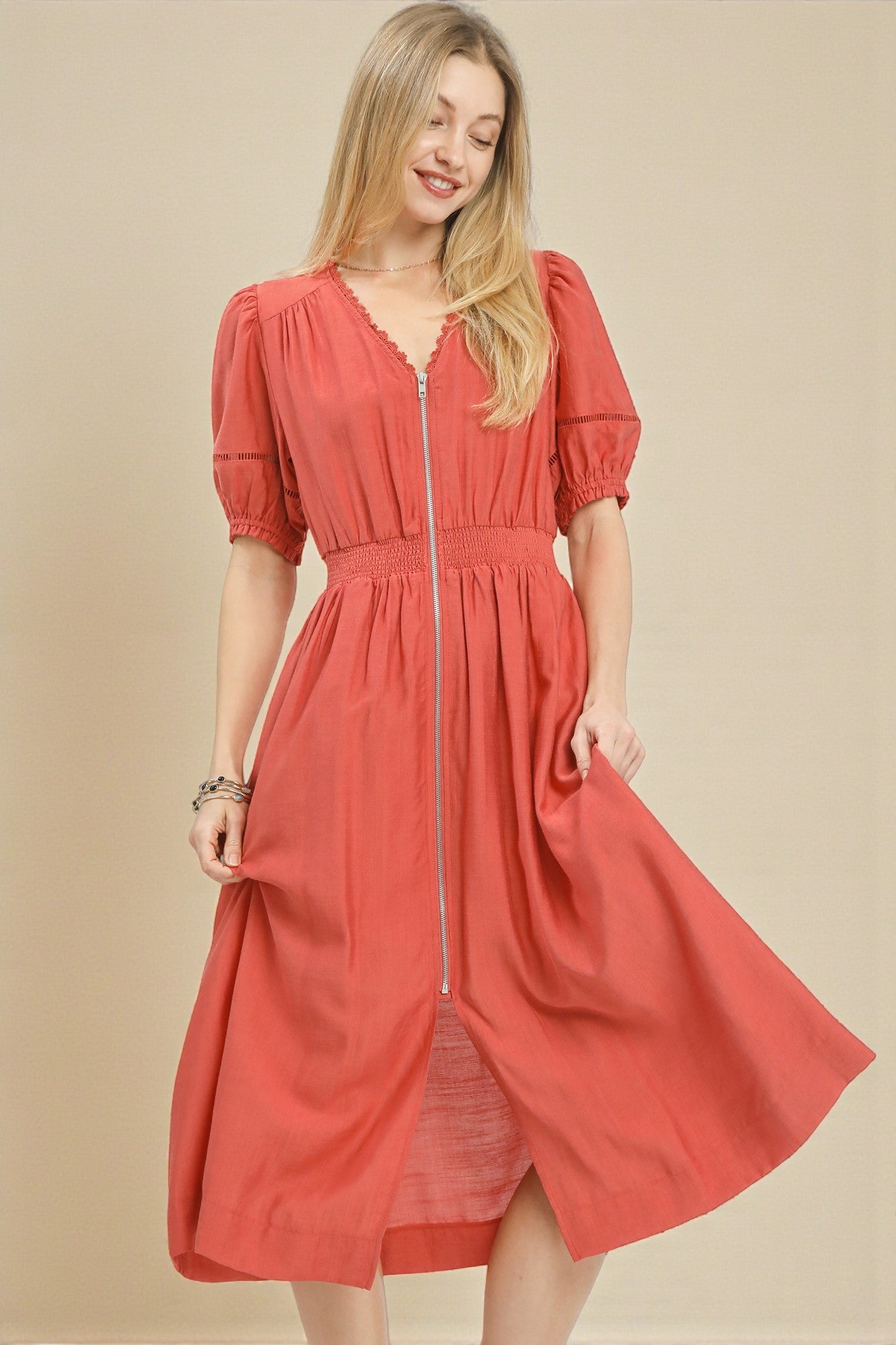Woman wearing a coral dress with a zipper on a beige background