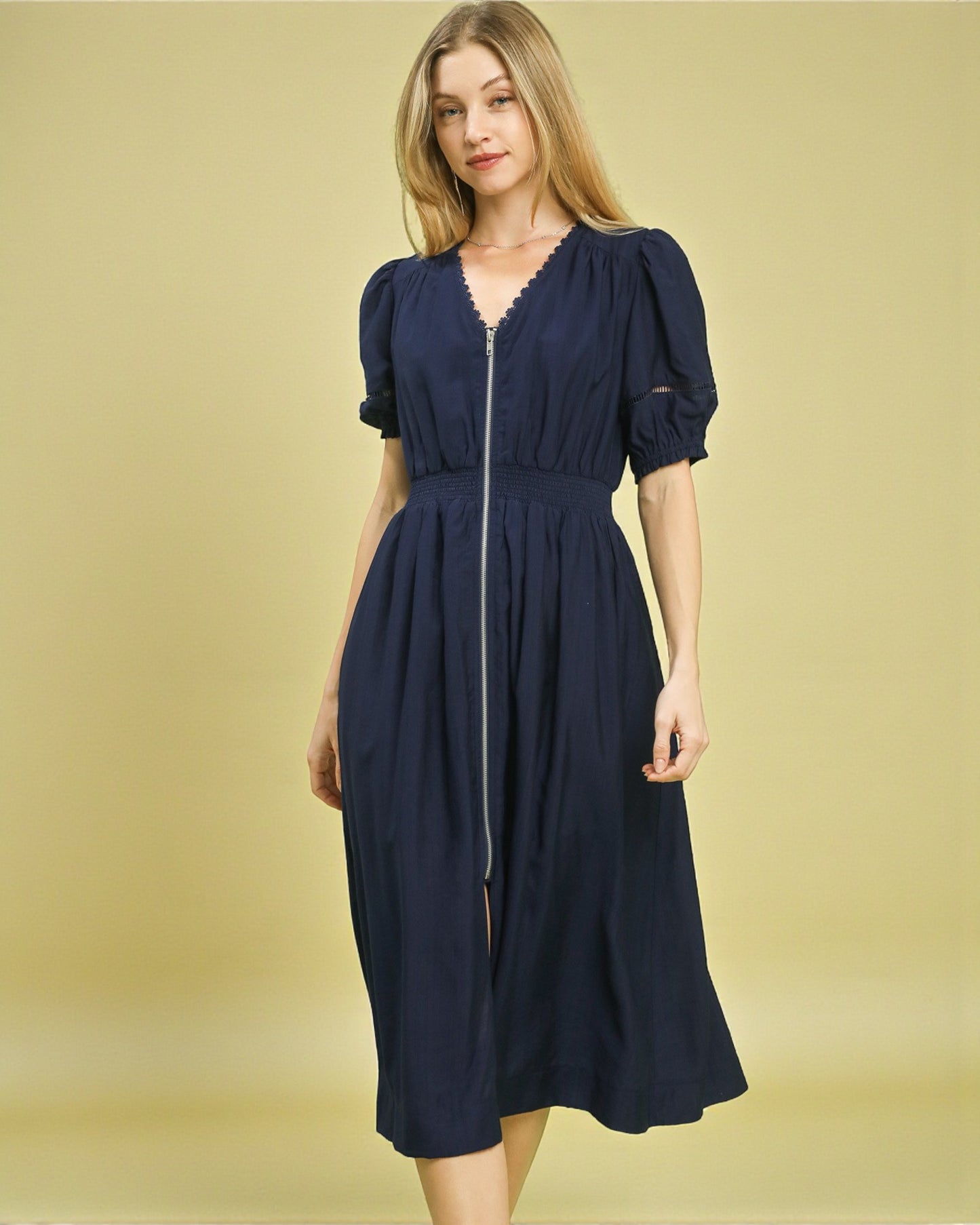 Woman wearing a navy blue dress against a gold background