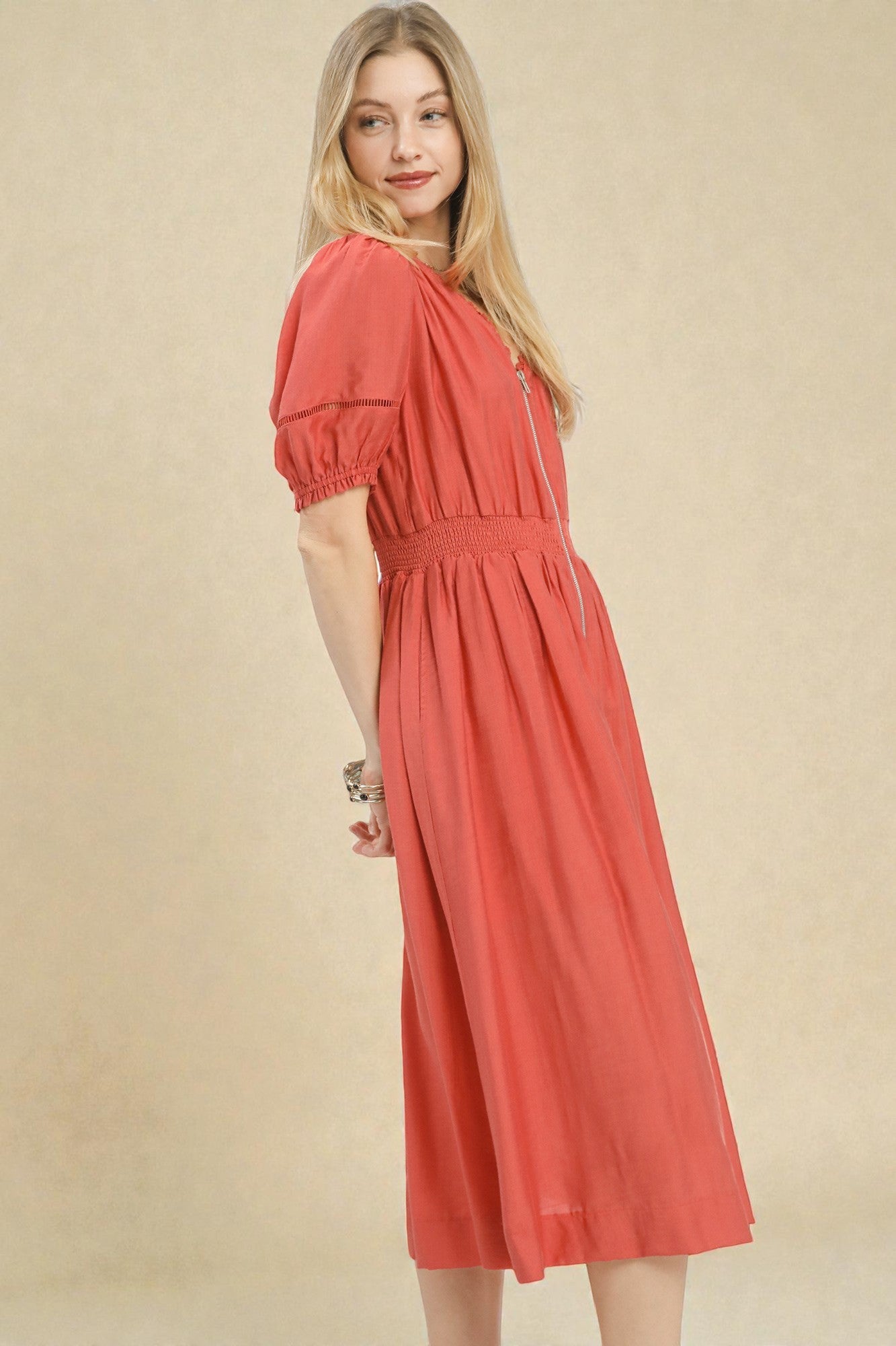 Woman wearing a coral dress against a beige background