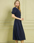 Woman wearing a navy blue dress against a beige wall.