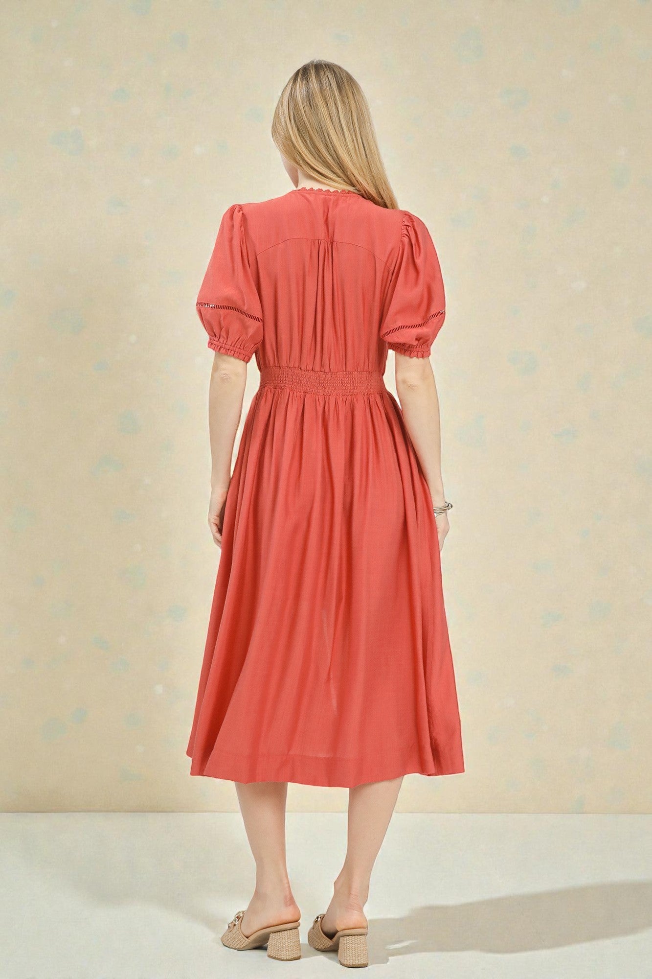 Woman wearing a coral dress against a beige background