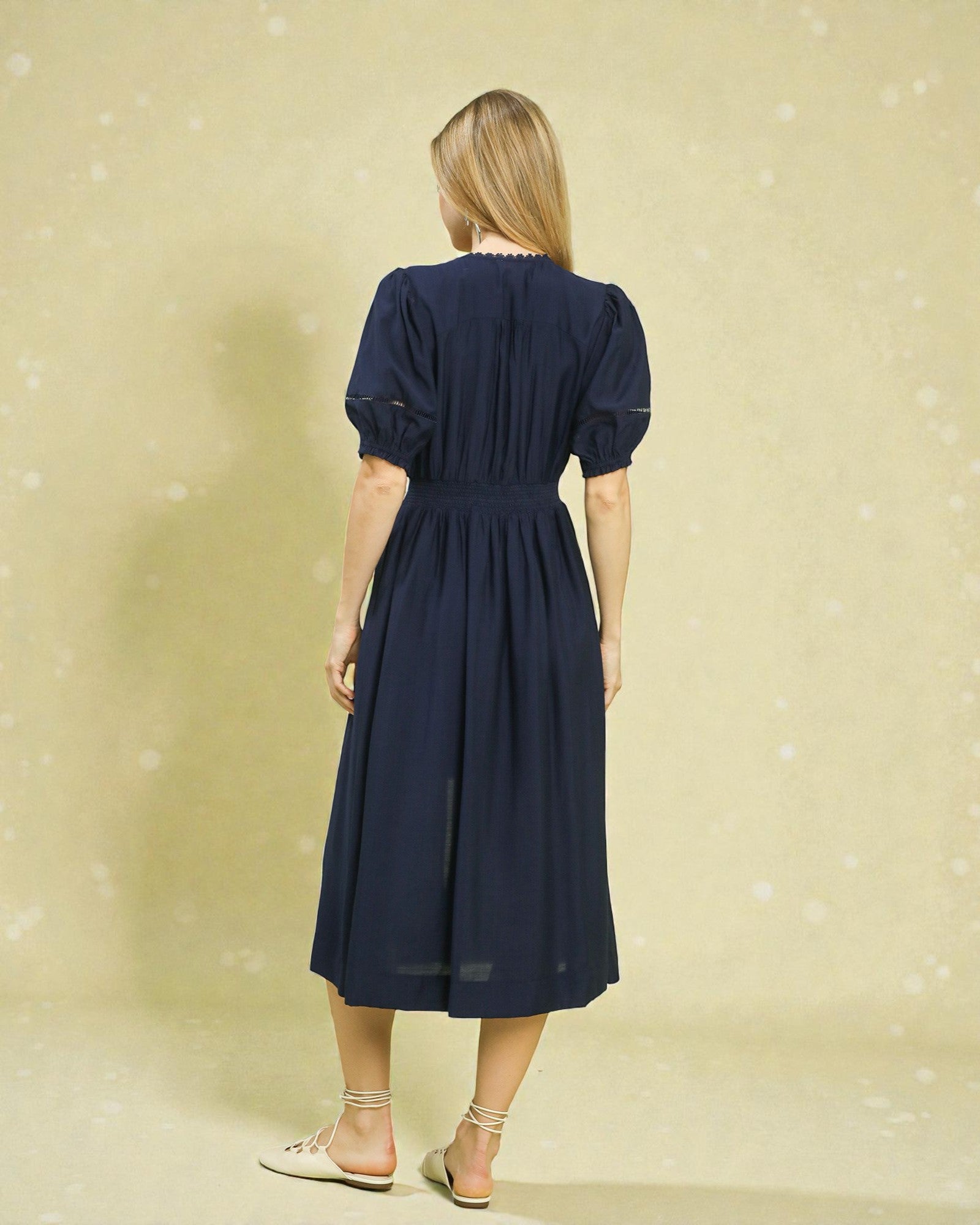 Woman wearing a navy dress against a beige background