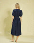 Woman wearing a navy dress against a beige background