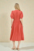 Woman wearing a coral dress against a beige background