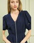 Woman wearing a navy blue dress with a zipper detail against a neutral background