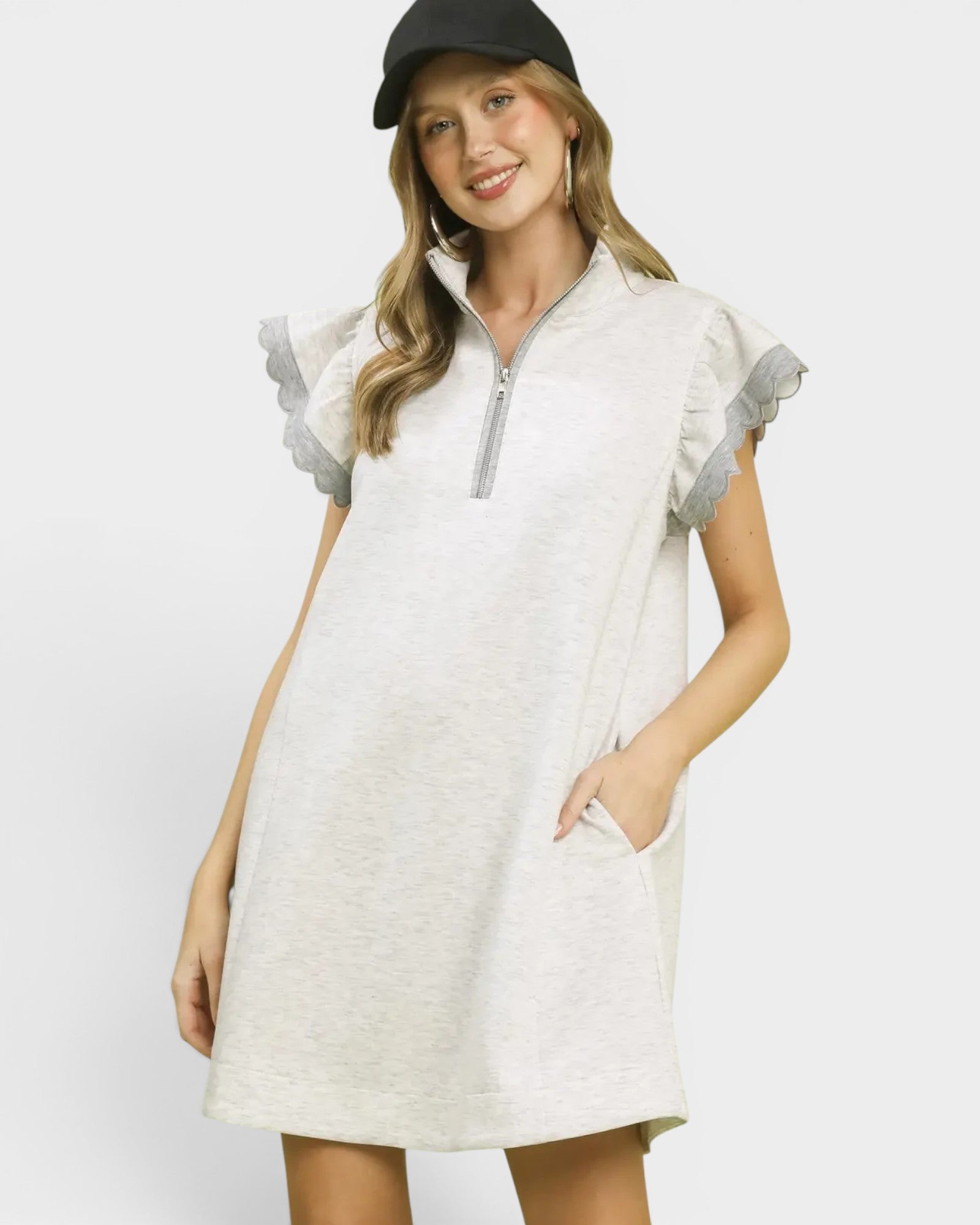 Woman wearing a white dress with gray accents on a plain background