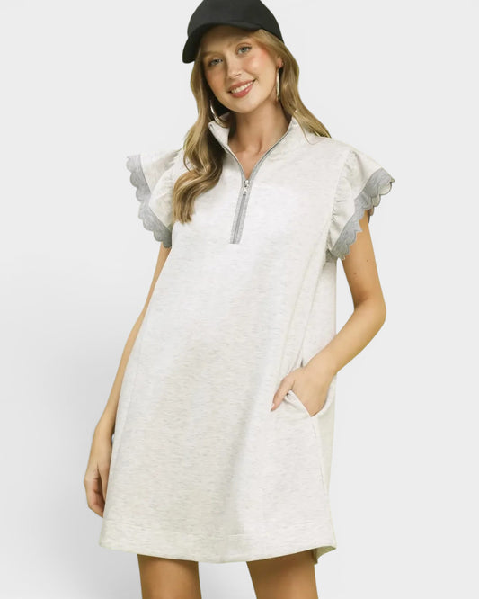 Woman wearing a white dress with gray accents on a plain background