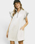 Woman wearing a white dress with gray accents on a plain background
