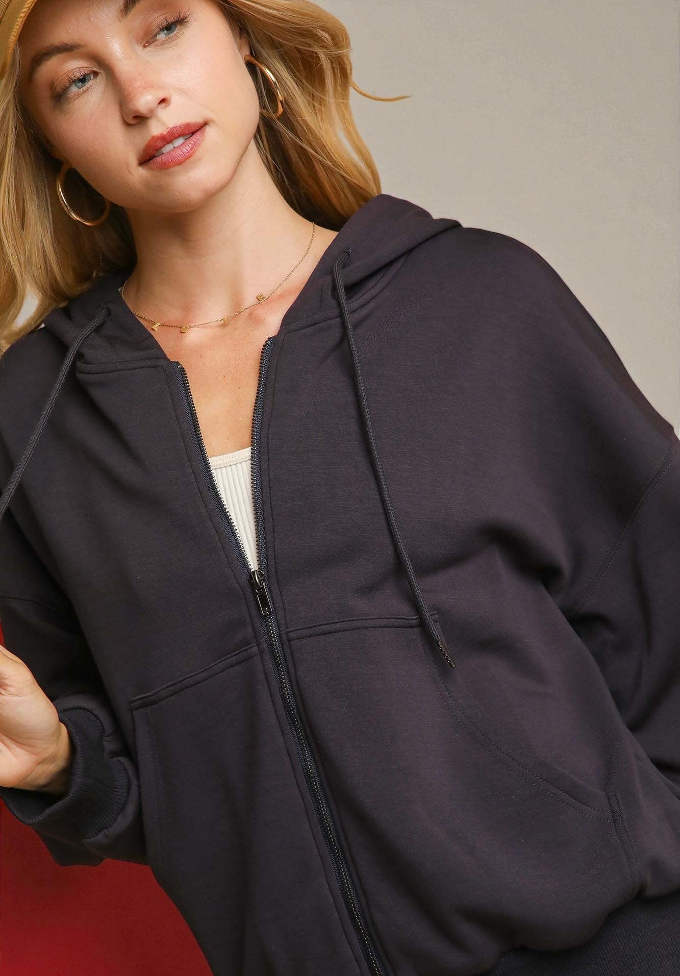 Woman wearing a charcoal gray hoodie against a neutral background