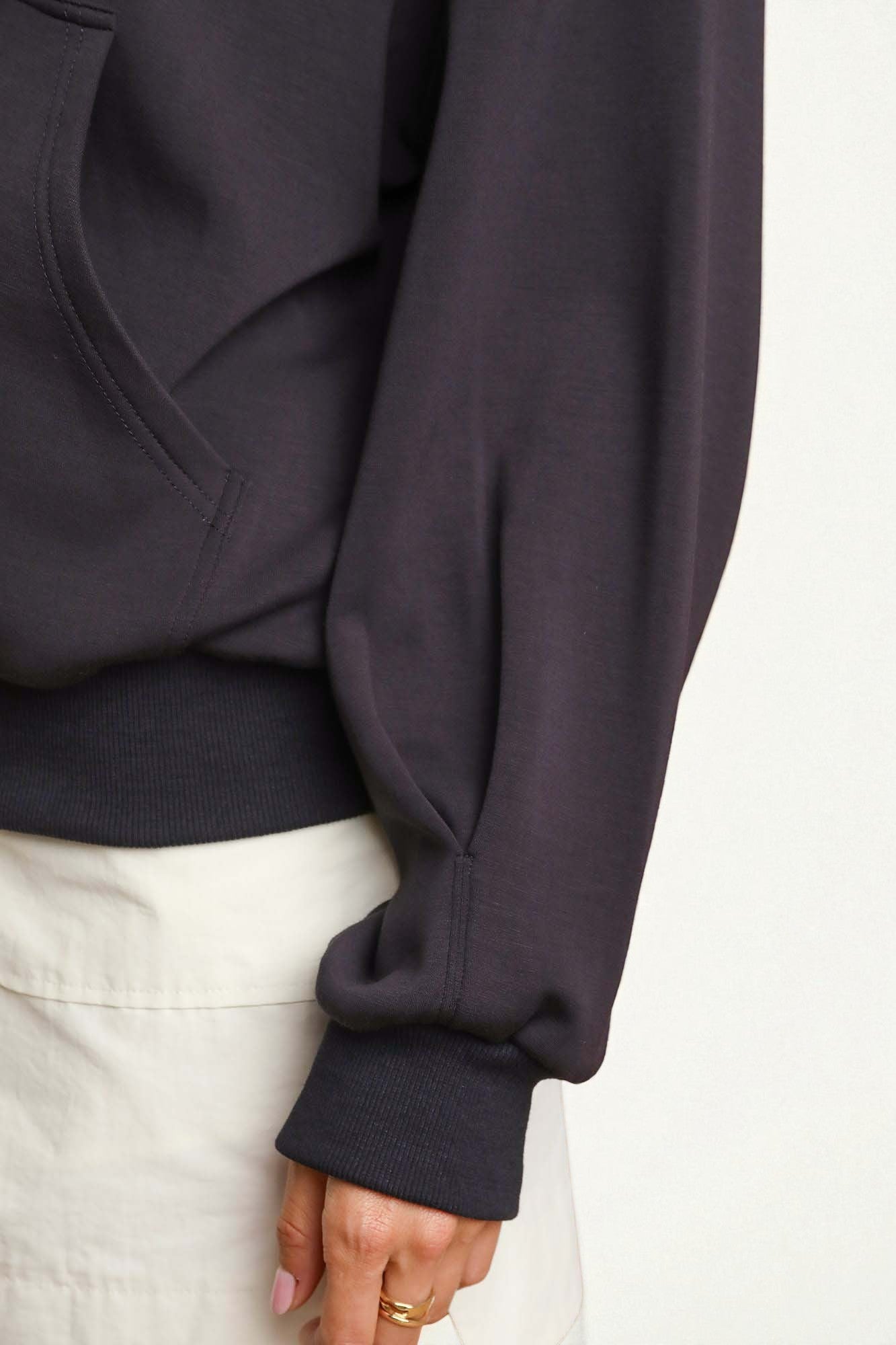 Dark black hoodie with white pants on a plain background