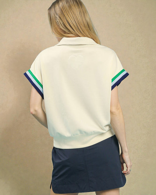 Woman wearing a cream-colored polo shirt with green and blue stripes on a beige background