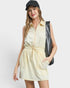Woman wearing a light yellow sleeveless dress with a black cap and bag on a white background